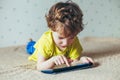 Little cute boy in a green T-shirt playing games on a tablet and watching cartoons. addiction concept Royalty Free Stock Photo