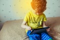 Little cute boy in a green T-shirt playing games on a tablet and watching cartoons. addiction concept Royalty Free Stock Photo