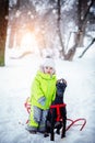 Little cute boy with his black dog friends in the winter forest Royalty Free Stock Photo