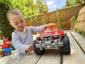 A little cute boy of one and a half years plays with toy car at the playground. Adorable toddler playing with cars and toys