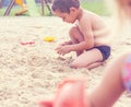 Little cute boy with plastic spatula in hand makes sand castle at the beach. Royalty Free Stock Photo