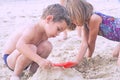 Little cute boy with plastic spatula in hand makes sand castle at the beach. Royalty Free Stock Photo