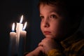 Little cute boy praying in front of a burning candle Royalty Free Stock Photo