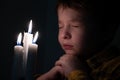 Little cute boy praying in front of a burning candle Royalty Free Stock Photo