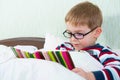 Little cute boy reading book in bed Royalty Free Stock Photo