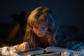 A little cute boy reading a book lying on the bed. Child reading a book on bedtime night. Kids development of the Royalty Free Stock Photo