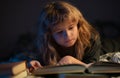 A little cute boy reading a book lying on the bed. Kids development of the imagination. Royalty Free Stock Photo