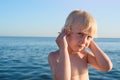 Little cute boy with seashell in hand on background of the sea. Child listening to sea Royalty Free Stock Photo