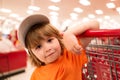 Little cute boy with shopping cart full of fresh organic vegetables and fruits standing in grocery department of food Royalty Free Stock Photo