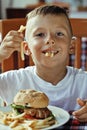 little cute boy 6 years old with hamburger and french fries maki Royalty Free Stock Photo