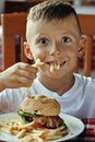 Little cute boy 6 years old with hamburger and Royalty Free Stock Photo