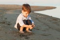 Little cute boy 3 years old plays with sand on the beach in the evening Royalty Free Stock Photo