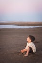 Little cute boy 3 years old plays with sand on the beach in the evening, he is look up. Vertical, copy space Royalty Free Stock Photo