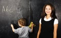 little cute boy with young teacher in classroom studying at blac Royalty Free Stock Photo