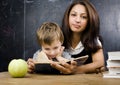 Little cute boy with young teacher in classroom studying at blackboard smiling Royalty Free Stock Photo