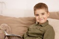 Little and cute caucasian boy reading a book on the bed at home. Interior and clothes in natural earth colors. Cozy Royalty Free Stock Photo