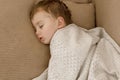 Little, cute caucasian boy sleeping on couch at home. Child taking day nap. Kid resting, relaxing. Sweet dreams, daily