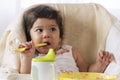 Little child celebrating her first birthday with cake at home. Baby adorable girl with apron holding spoon in her hand while