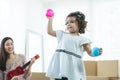 Little cute child daughter holding colorful balls in hands and dancing while young mother playing ukulele, having fun together. Royalty Free Stock Photo