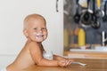 Little cute child experiences happiness and joy, eats yogurt with a spoon soiling Royalty Free Stock Photo