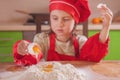 Little cute child girl chef kneading dough on board. Flour and eggs Royalty Free Stock Photo