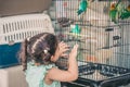 Little Cute Child Looking Colorful Parrot On Cage.