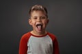 Little cute child. shows his tounge. is isolated on grey background.