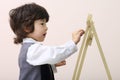 Little cute concentrated boy draws by chalk at chalkboard