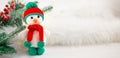 Little cute crocheted snowman in a red hat and scarf on a white background