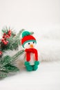 Little cute crocheted snowman in a red hat and scarf on a white background