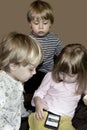 Little cute curious blonde triplets watch cartoons on smartphone Royalty Free Stock Photo