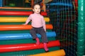 Little cute curly baby girl playing in a children`s entertainment center in the game maze. The child plays in the playground