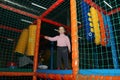 Little cute curly baby girl playing in a children`s entertainment center in the game maze. The child plays in the playground