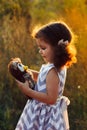 Little cute curly girl hugd a fluffy toy owl. Toddler girl play with sweet doll. A beautiful sunlight, warm colours. Autumn time