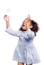 Little cute fashionable african american girl in blue dress catches soap bubbles on white background Royalty Free Stock Photo