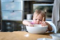 Little cute funny girl licking the dough from her finger helping mother prepare pie cake in kitchen, baking homemade Royalty Free Stock Photo