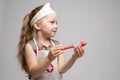 Little cute funny girl playing wearing doctor uniform holding toy syringe looking at camera Royalty Free Stock Photo