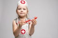 Little cute funny girl playing wearing doctor uniform holding toy syringe looking at camera Royalty Free Stock Photo