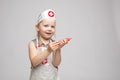 Little cute funny girl playing wearing doctor uniform holding toy syringe looking at camera Royalty Free Stock Photo