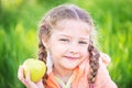 Little cute girl on a background of green grass with an apple Royalty Free Stock Photo