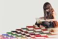 A wise little cute girl kid in a black dress sitting on pile of book reading and learning knowledge and information