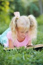 Little cute girl with blond hair reading a book in the outdoors. Royalty Free Stock Photo