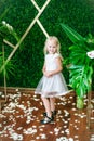 Little cute girl with blond hair in a white dress  and white flowers, lilies and orchids Royalty Free Stock Photo