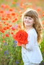 Little cute girl with a bouquet of poppies stands in a field Royalty Free Stock Photo