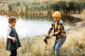 Little cute girl and boy catching a fish in the lake, river or pond. Funny kid wants to hold a fish in hands