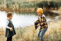 Little cute girl and boy catching a fish in the lake, river or pond. Funny kid wants to hold a fish in hands