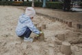 Little cute girl builds sand cakes at a playground