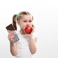 Little cute girl chooses apple over chocolate, preference of healthy food over unhealthy and unhealthy. Royalty Free Stock Photo