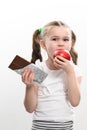 Little cute girl chooses apple over chocolate, preference of healthy food over unhealthy and unhealthy. Royalty Free Stock Photo