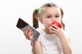 Little cute girl chooses apple over chocolate, preference of healthy food over unhealthy and unhealthy. Royalty Free Stock Photo